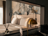 Doppelbett mit schwarzen Nachtlichtern und goldener Stehlampe